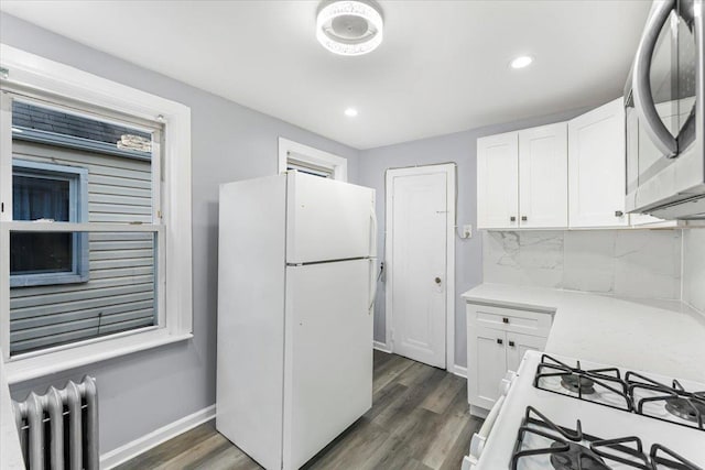 kitchen featuring white cabinets, dark hardwood / wood-style flooring, white appliances, and radiator