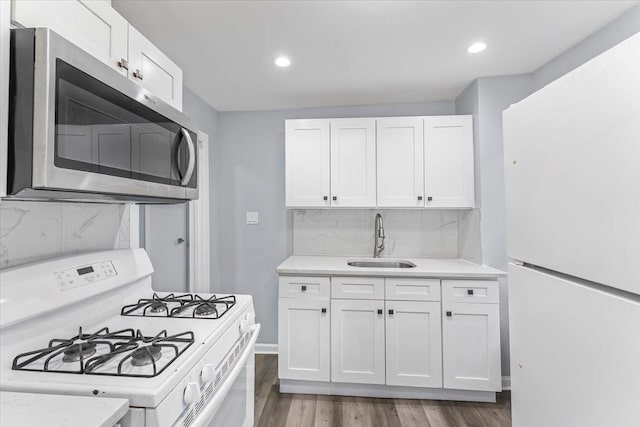 kitchen with dark hardwood / wood-style flooring, tasteful backsplash, white appliances, sink, and white cabinetry