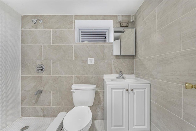 bathroom with toilet, vanity, tile walls, and tiled shower