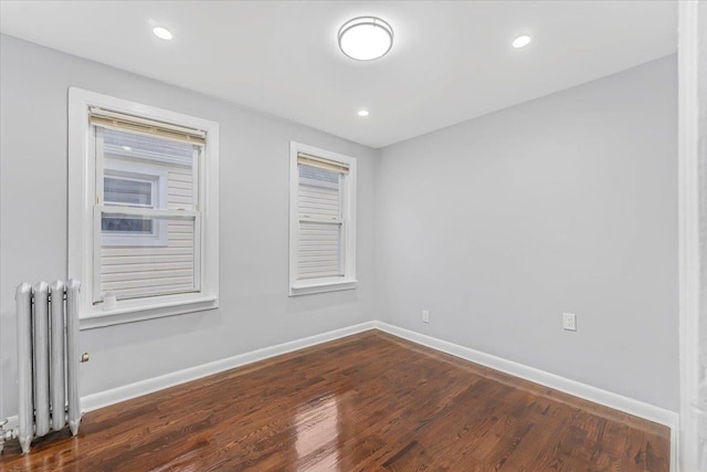 spare room featuring dark hardwood / wood-style floors and radiator heating unit