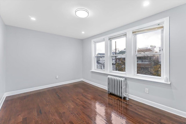 spare room with radiator and dark hardwood / wood-style floors