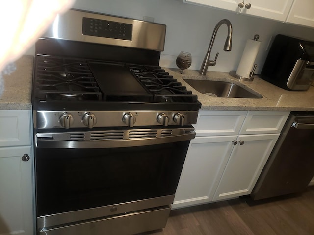 kitchen featuring light stone countertops, stainless steel appliances, white cabinetry, and dark wood-type flooring