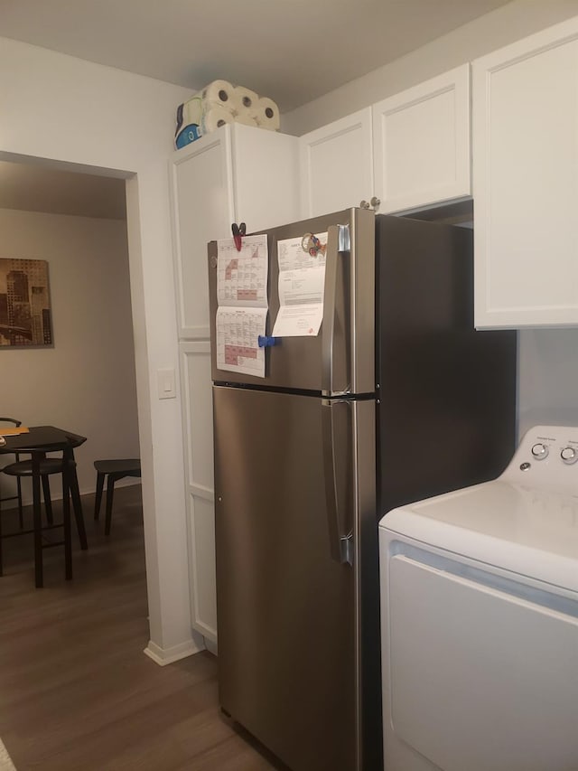 kitchen with dark hardwood / wood-style flooring, white cabinetry, washer / clothes dryer, and stainless steel refrigerator