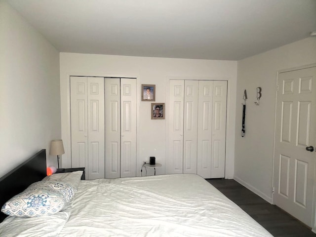 bedroom with multiple closets and dark hardwood / wood-style floors