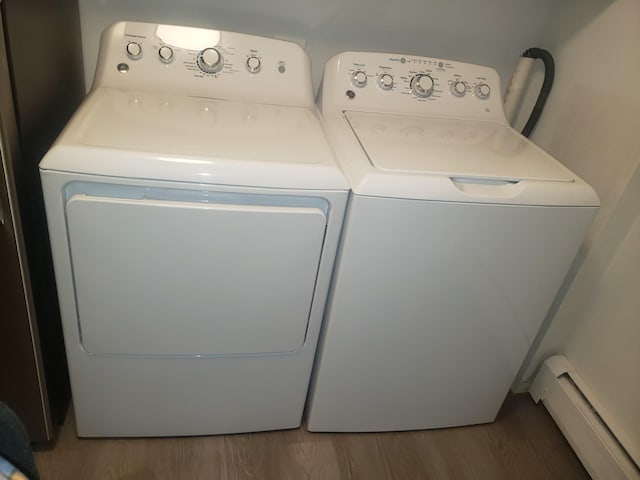 laundry area with dark wood-type flooring, separate washer and dryer, and a baseboard heating unit