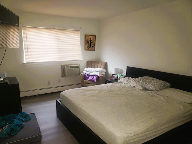 bedroom with wood-type flooring, a wall unit AC, and a baseboard radiator