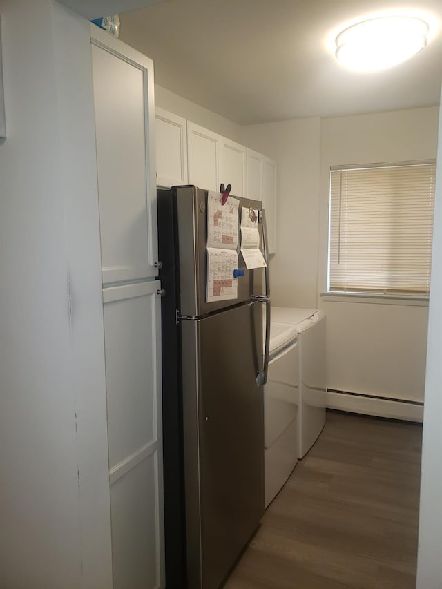 clothes washing area with hardwood / wood-style floors, cabinets, separate washer and dryer, and a baseboard heating unit