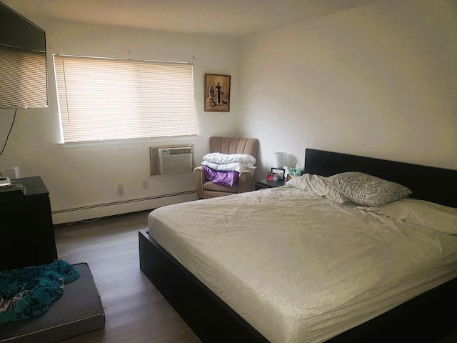 bedroom featuring a wall mounted AC, dark hardwood / wood-style flooring, and baseboard heating