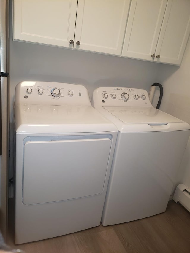 washroom featuring independent washer and dryer, cabinets, wood-type flooring, and a baseboard heating unit