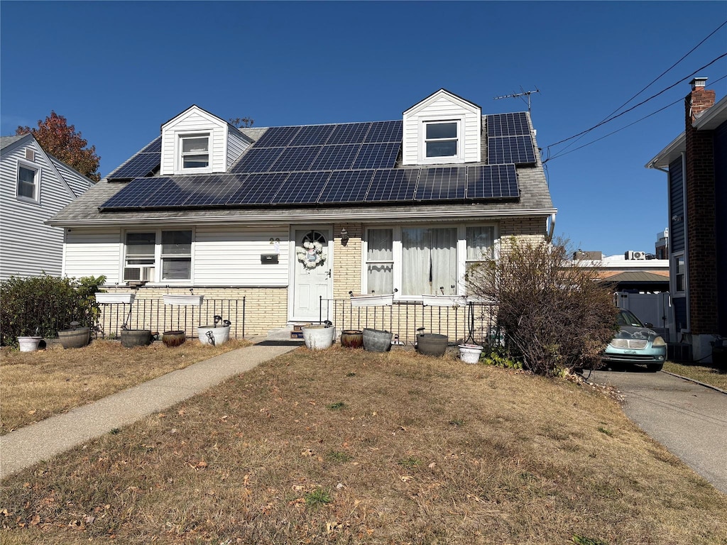 cape cod house featuring cooling unit, a front yard, and solar panels