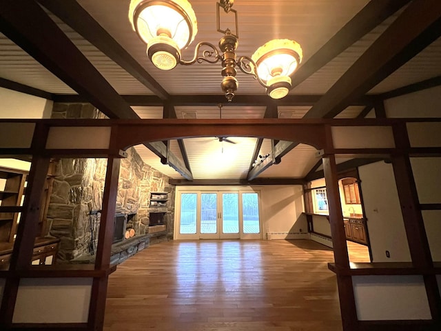 unfurnished living room with wood-type flooring, vaulted ceiling, a stone fireplace, and ceiling fan