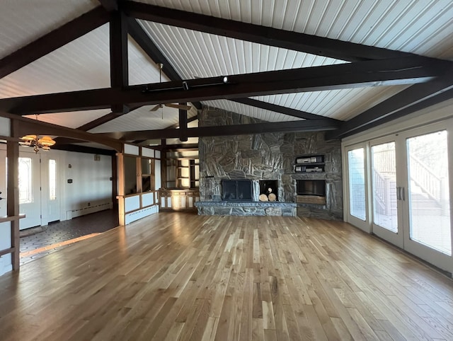 unfurnished living room featuring hardwood / wood-style floors, vaulted ceiling with beams, a stone fireplace, and baseboard heating