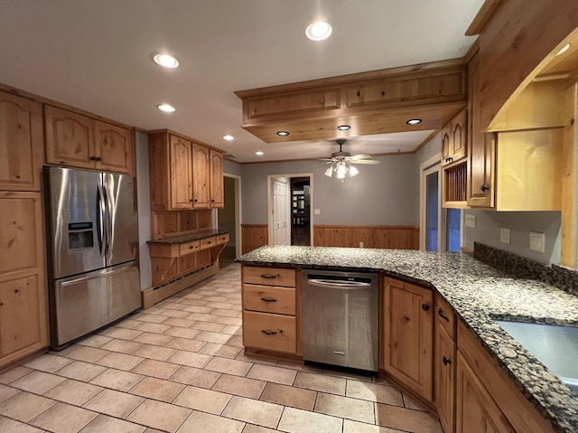 kitchen with ceiling fan, wood walls, kitchen peninsula, and appliances with stainless steel finishes