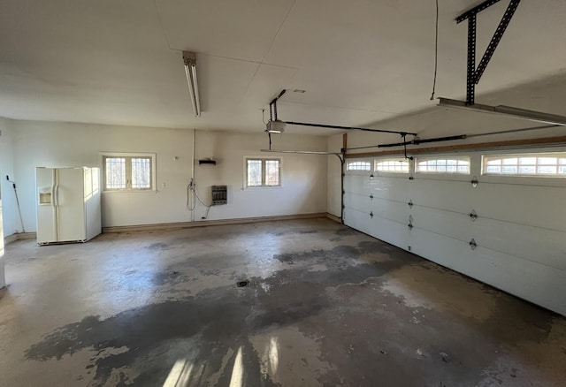 garage featuring white refrigerator with ice dispenser and a garage door opener