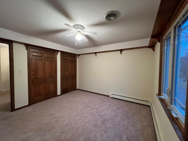 unfurnished bedroom with ceiling fan, two closets, light carpet, and a baseboard radiator