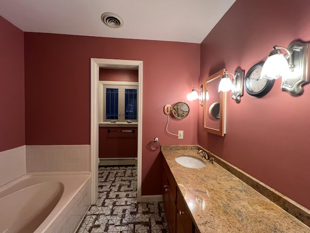 bathroom with tiled tub, vanity, and a baseboard radiator