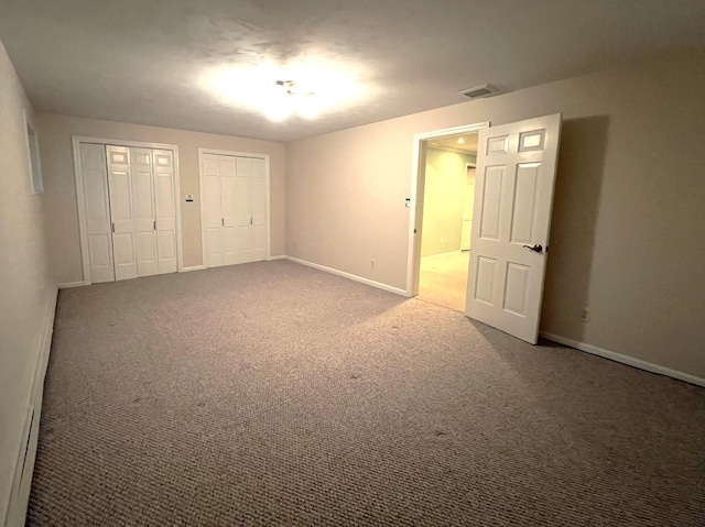 unfurnished bedroom featuring carpet and multiple closets