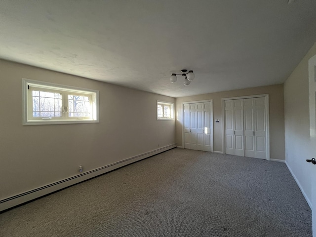 unfurnished bedroom featuring multiple closets, carpet floors, and a baseboard radiator