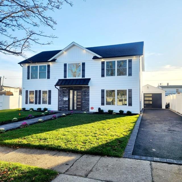 view of front of home with a garage, an outdoor structure, and a front yard