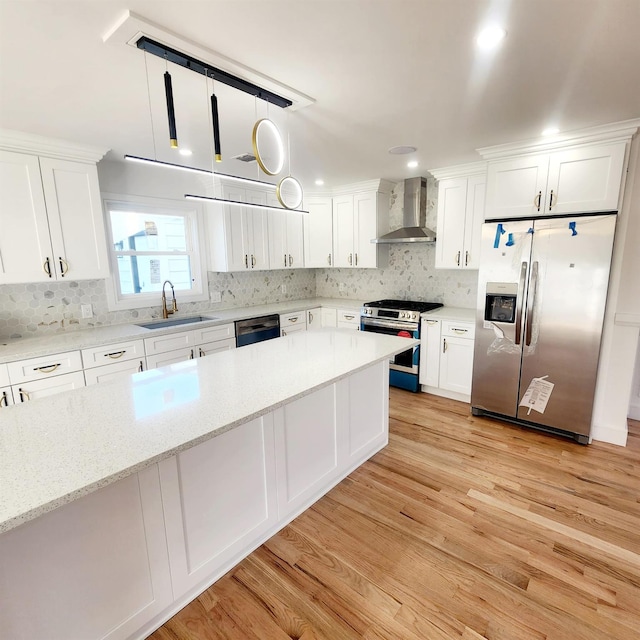 kitchen featuring pendant lighting, wall chimney range hood, light wood-type flooring, appliances with stainless steel finishes, and white cabinetry