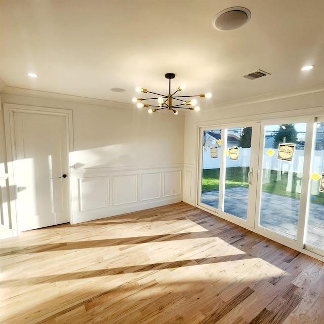 unfurnished room featuring a chandelier, crown molding, and light hardwood / wood-style floors