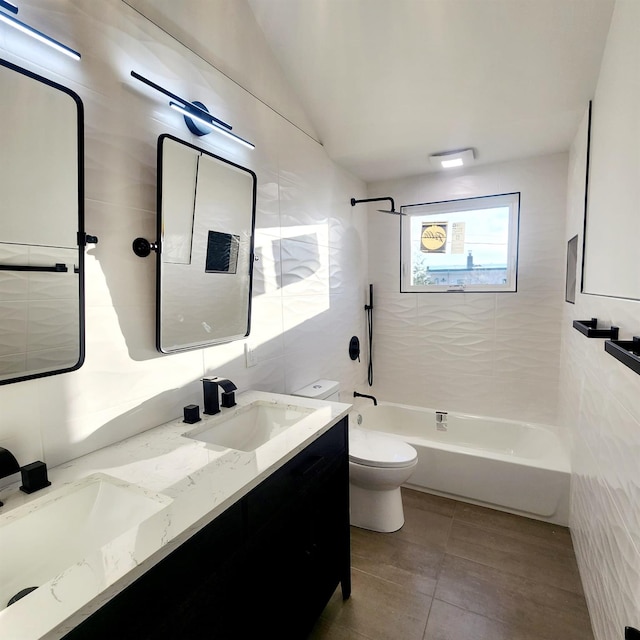 full bathroom featuring vanity, vaulted ceiling, tiled shower / bath combo, toilet, and tile walls