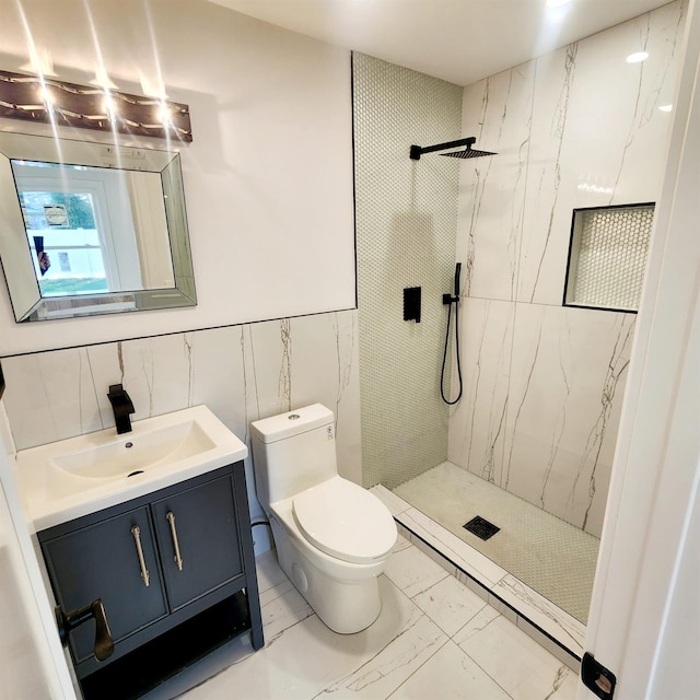 bathroom featuring a tile shower, vanity, toilet, and tile walls