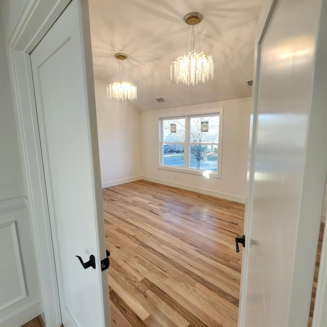 unfurnished dining area with a chandelier and light hardwood / wood-style floors