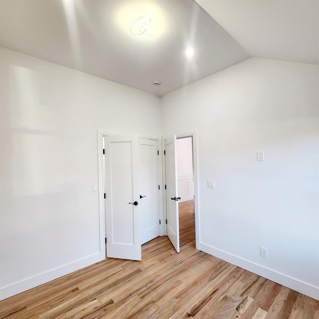 spare room with light hardwood / wood-style floors and vaulted ceiling