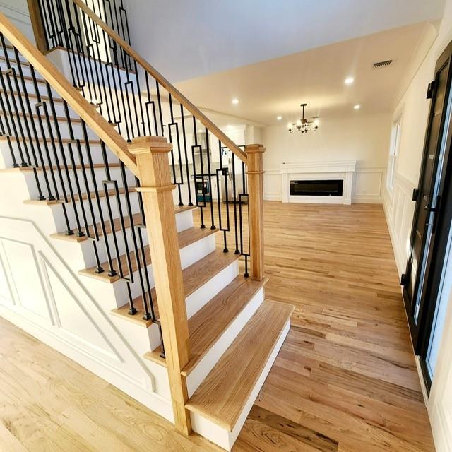 stairway with hardwood / wood-style floors and an inviting chandelier