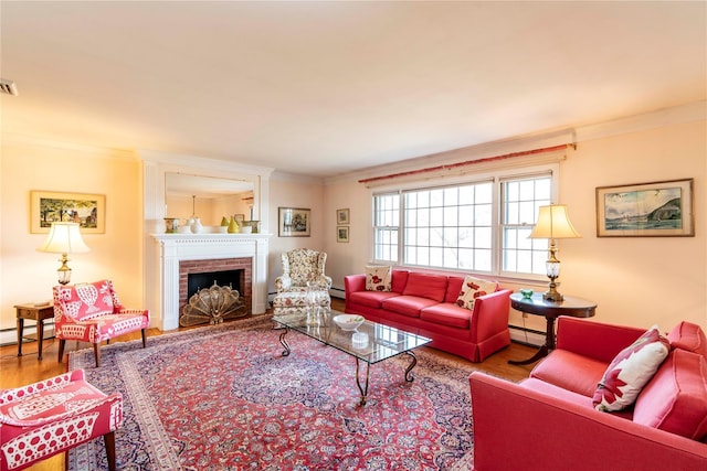 living room with hardwood / wood-style flooring, crown molding, a baseboard radiator, and a brick fireplace