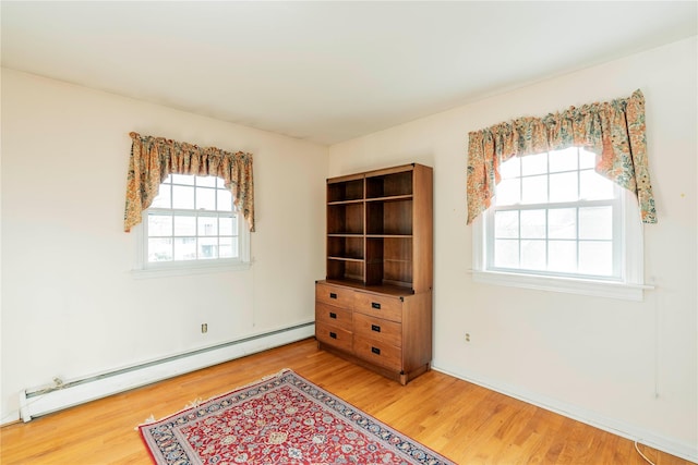 spare room featuring wood-type flooring and baseboard heating