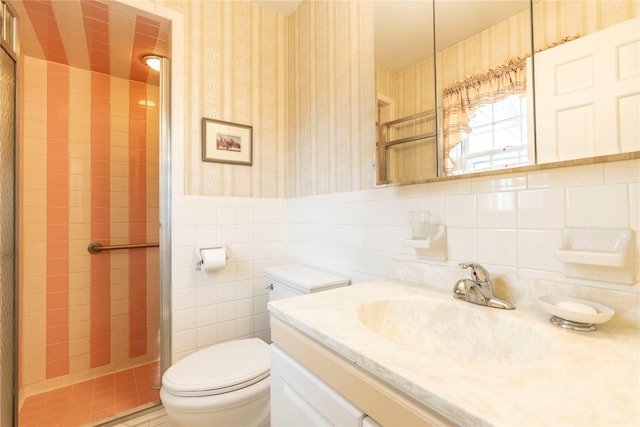 bathroom featuring a shower with door, vanity, tile walls, and toilet