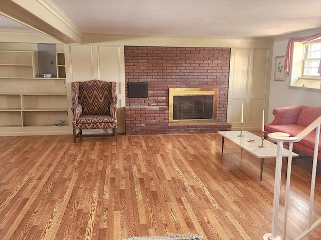 living area featuring a brick fireplace, wood-type flooring, and ornamental molding