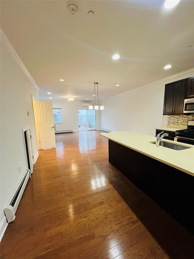 kitchen with tasteful backsplash, a baseboard heating unit, sink, hanging light fixtures, and stainless steel appliances