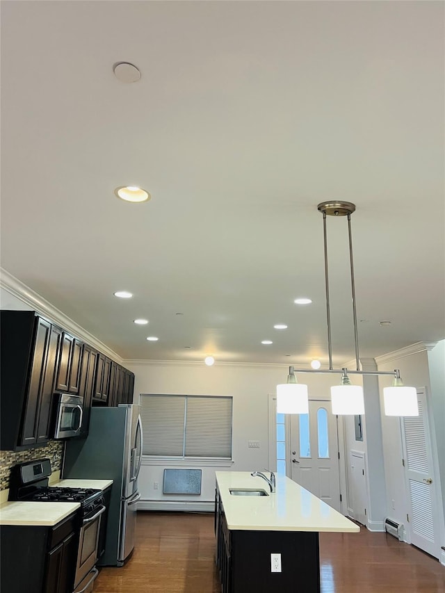 kitchen featuring an island with sink, appliances with stainless steel finishes, pendant lighting, crown molding, and sink