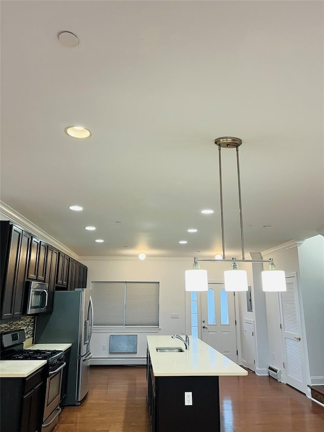 kitchen with stainless steel appliances, sink, hanging light fixtures, backsplash, and a center island with sink