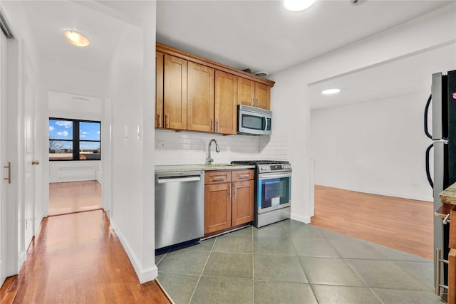 kitchen featuring light stone countertops, appliances with stainless steel finishes, tasteful backsplash, and wood-type flooring