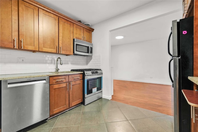 kitchen featuring light stone countertops, sink, dark wood-type flooring, stainless steel appliances, and decorative backsplash