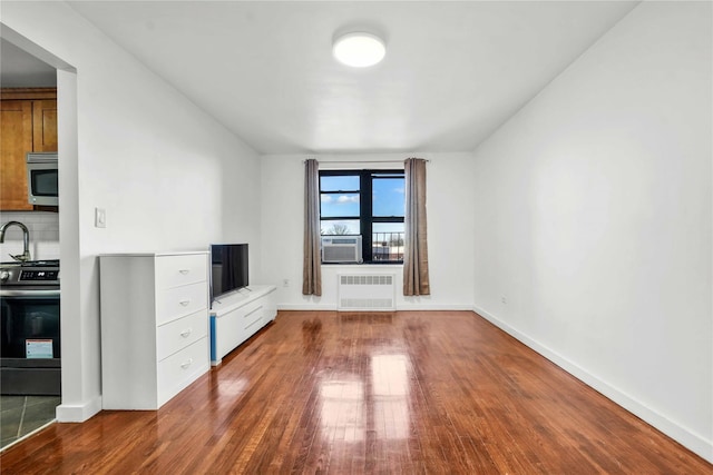 unfurnished living room featuring cooling unit, dark hardwood / wood-style flooring, and radiator heating unit