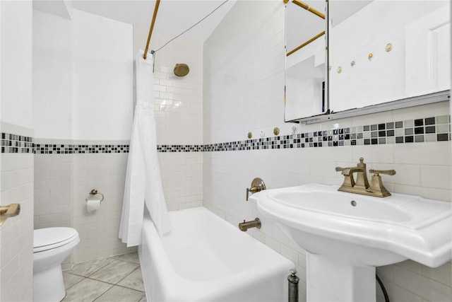 bathroom with tile patterned floors, shower / bath combo, tile walls, and toilet