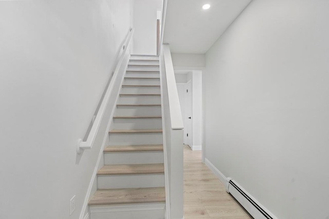 stairs featuring wood-type flooring and a baseboard radiator