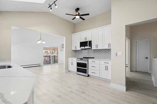 kitchen with tasteful backsplash, pendant lighting, lofted ceiling, white cabinets, and appliances with stainless steel finishes