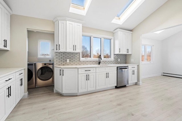 kitchen featuring sink, stainless steel dishwasher, vaulted ceiling, washer and clothes dryer, and white cabinets