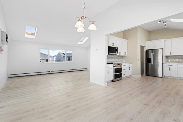 kitchen featuring decorative backsplash, stainless steel appliances, lofted ceiling with skylight, and white cabinetry