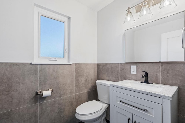 bathroom with vanity, tile walls, and toilet