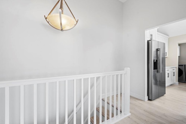 hallway with washer / dryer and light hardwood / wood-style flooring