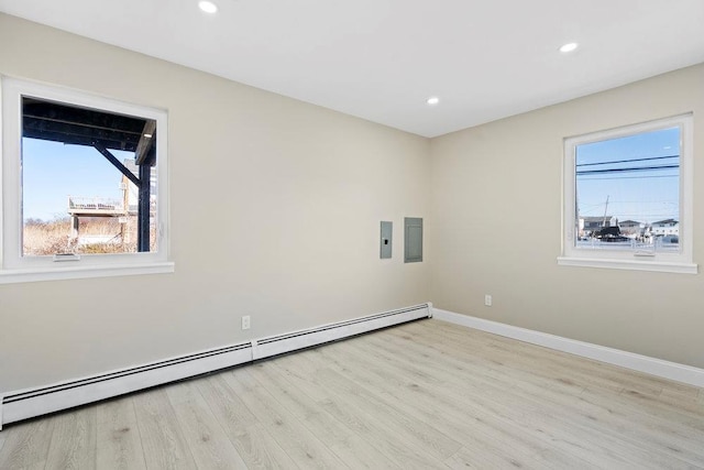 empty room with light wood-type flooring, a wealth of natural light, and a baseboard radiator