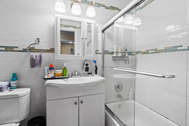 full bathroom featuring vanity, toilet, enclosed tub / shower combo, tile walls, and tasteful backsplash