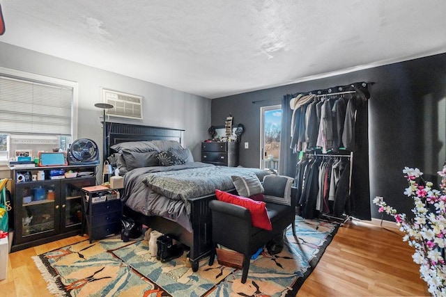 bedroom featuring a wall mounted AC and hardwood / wood-style floors